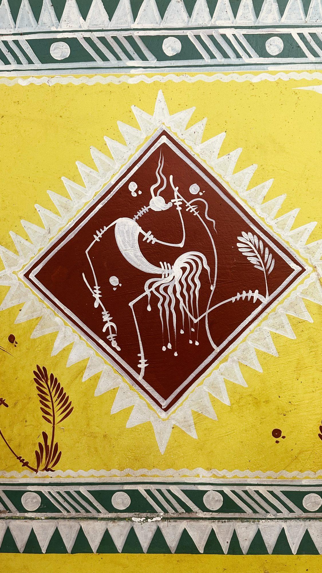 Folk-art wall painting of a dancer in a diamond frame, white on brown, with a sunburst border and green zig-zag bands