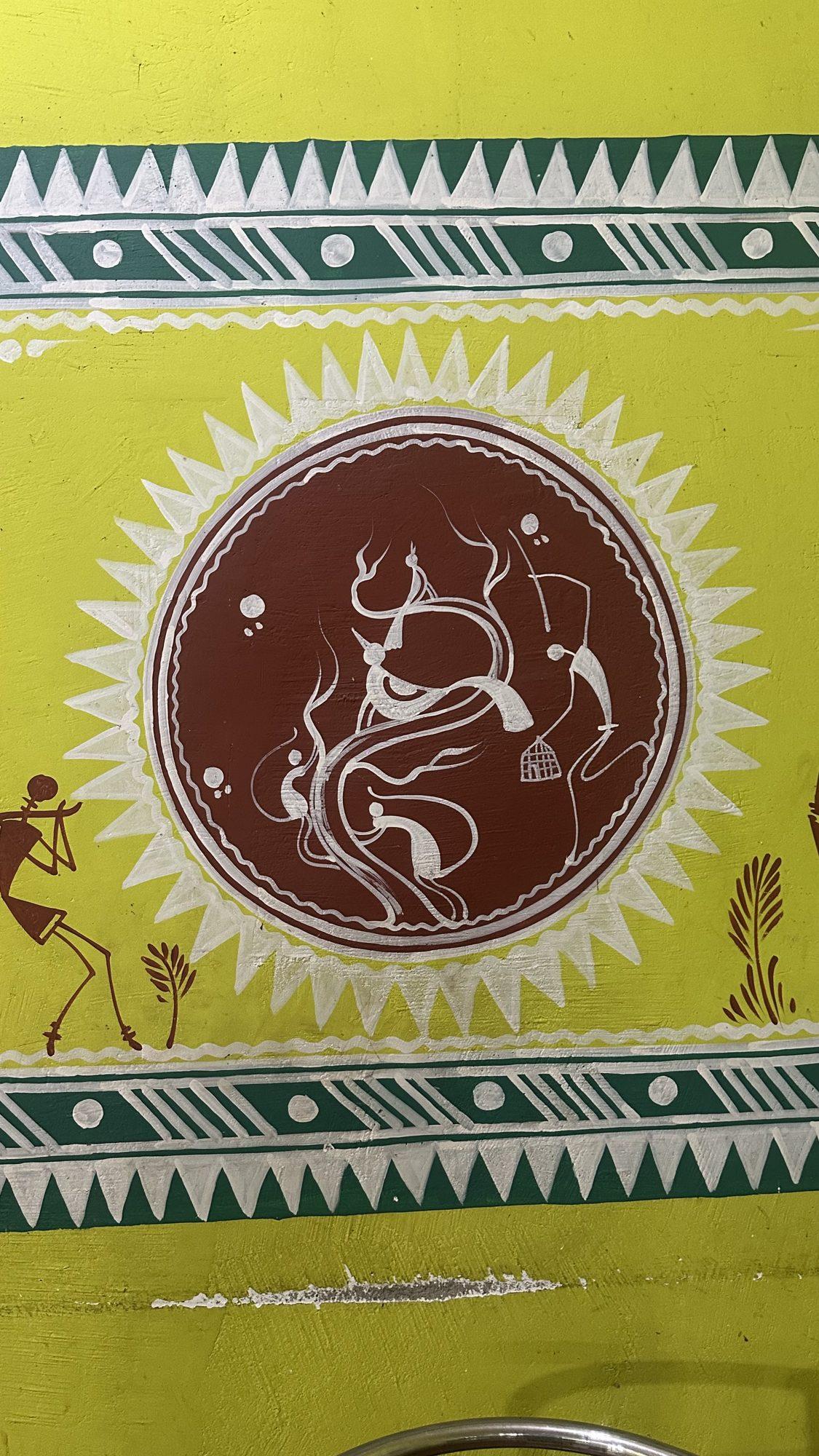 Folk-art wall painting of figures around a fire inside a circle