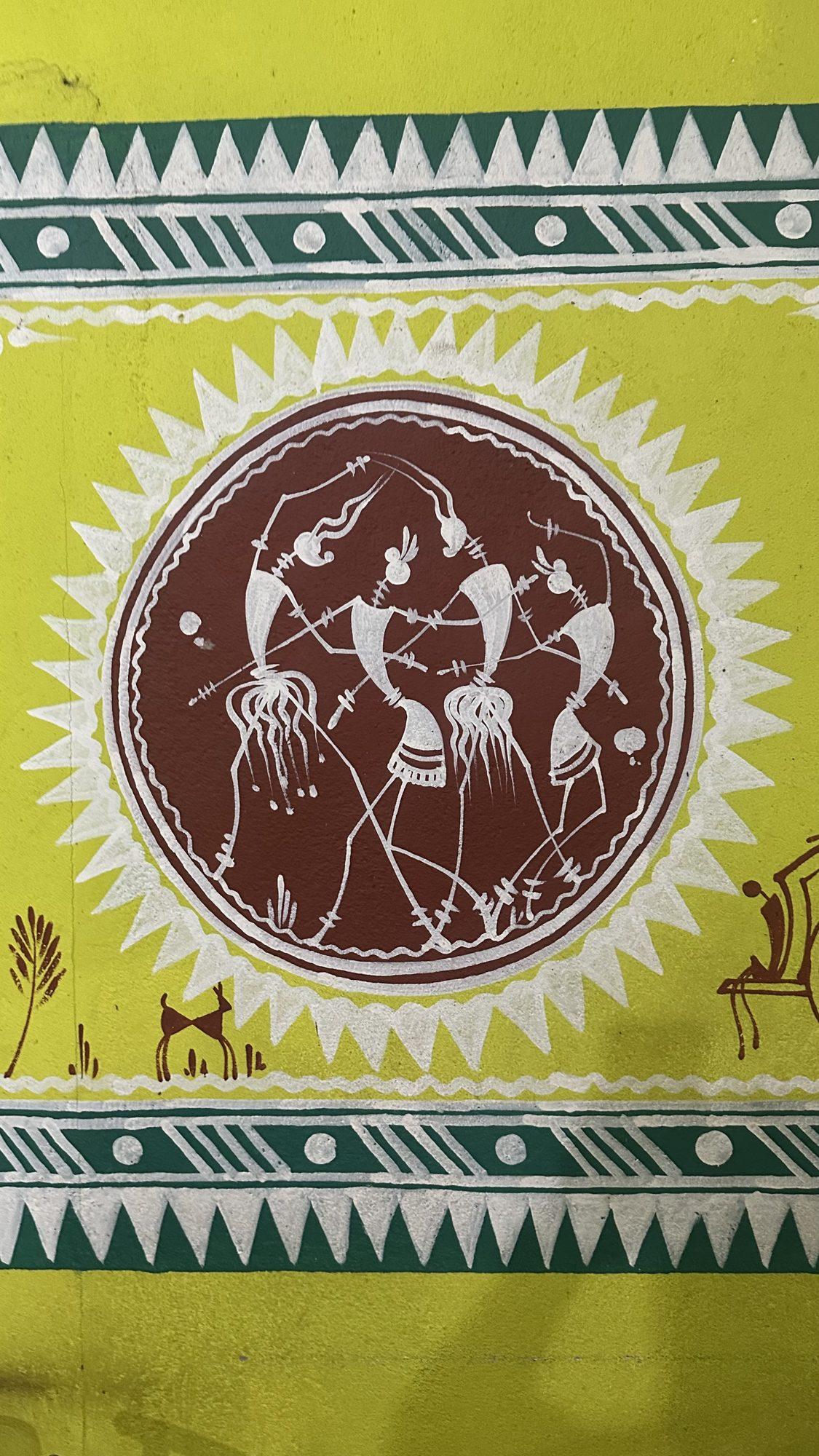 Folk-art wall painting of a group of dancers inside a circle with a sunburst border