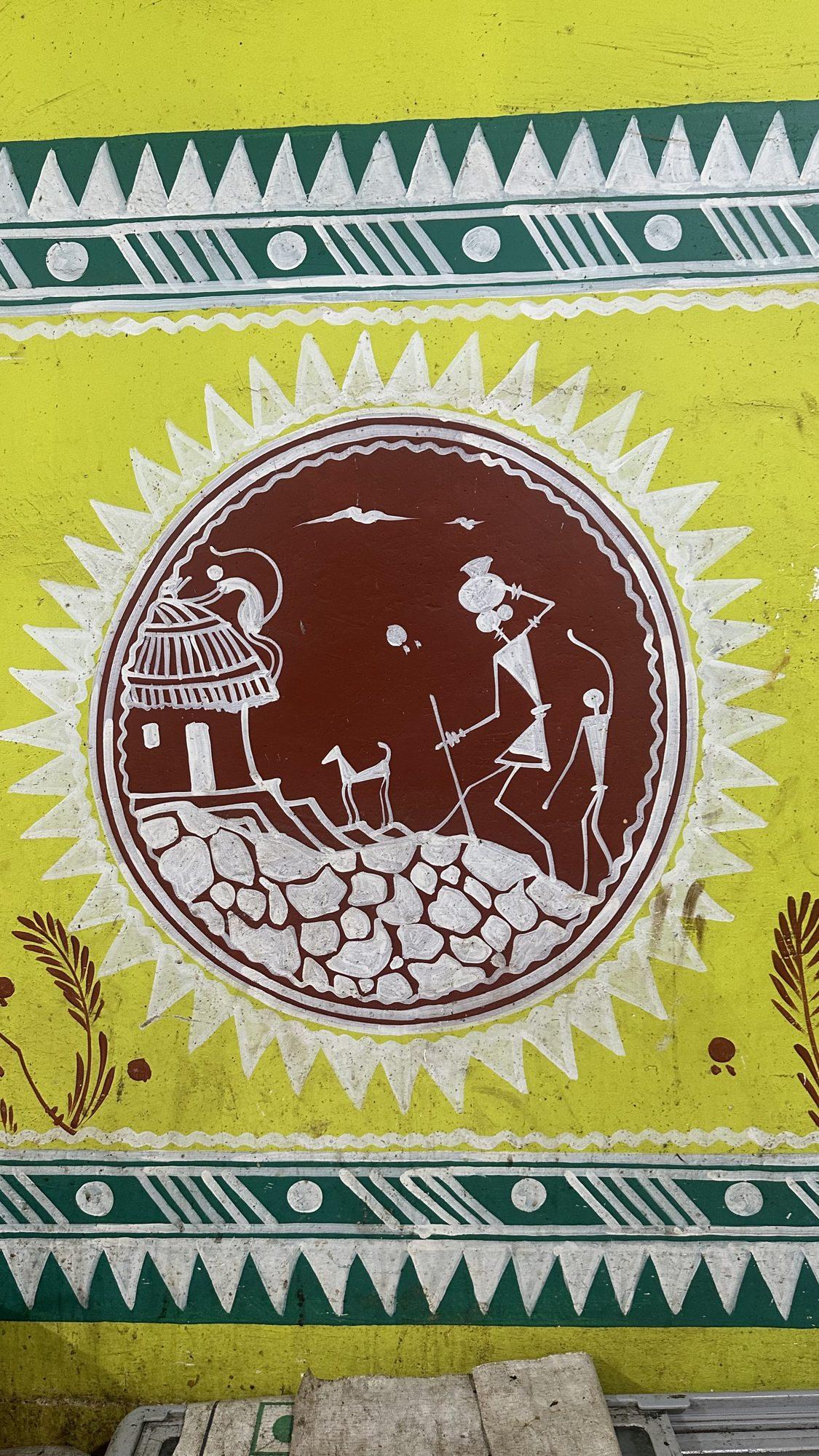 Folk-art wall painting of a village scene with a hut, a dog and a villager inside a circle