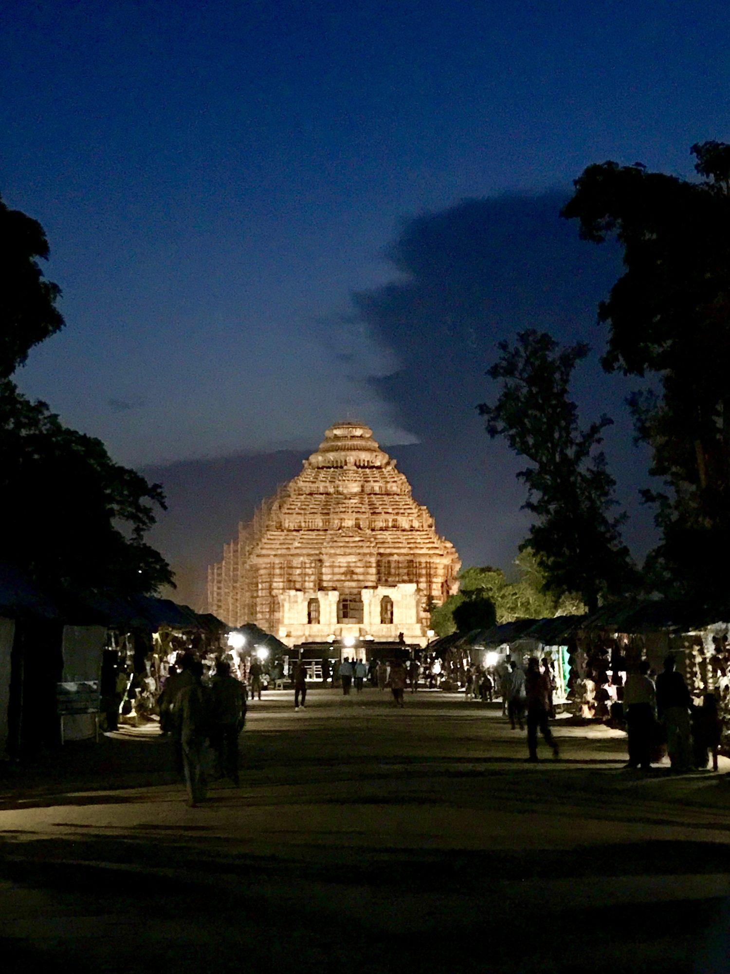 Konark Sun Temple glowing at dusk at the end of a lane of market stalls
