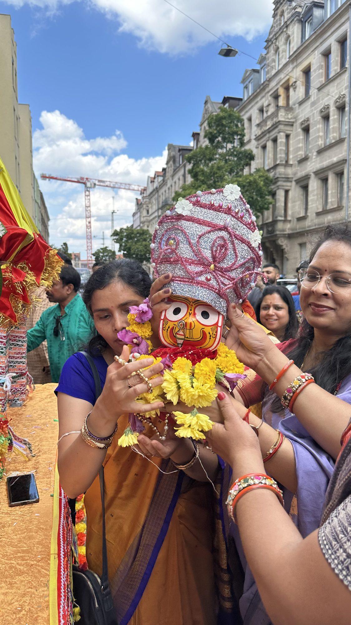 Women gently holding a decorated Lord Jagannath idol during the Rath Yatra celebration