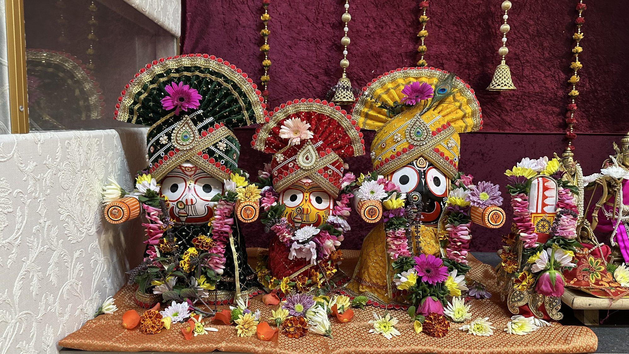 Lord Jagannath, Balabhadra and Subhadra decorated with colourful crowns and flowers on an altar